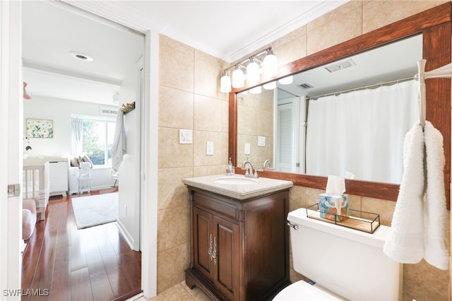 bathroom with visible vents, tile walls, vanity, and wood finished floors