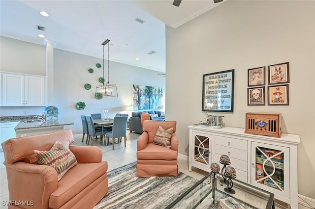 sitting room featuring crown molding, visible vents, a towering ceiling, baseboards, and ceiling fan with notable chandelier