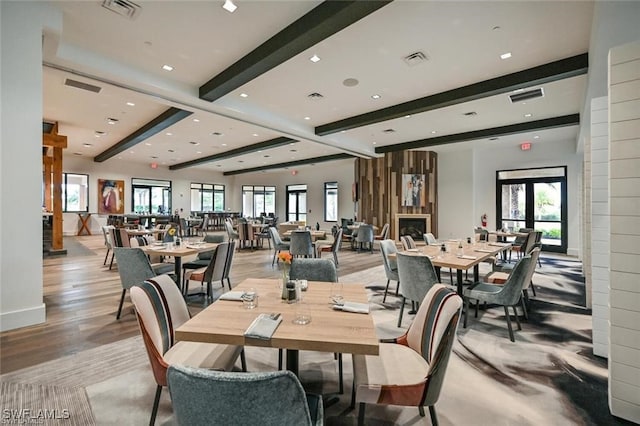 dining space featuring visible vents, light wood-type flooring, and beam ceiling