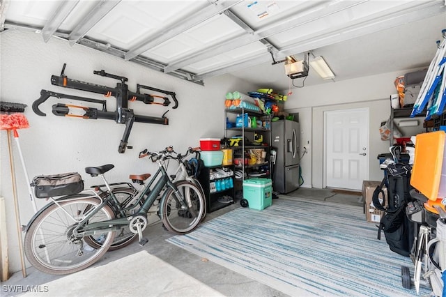 garage with a garage door opener and stainless steel refrigerator with ice dispenser