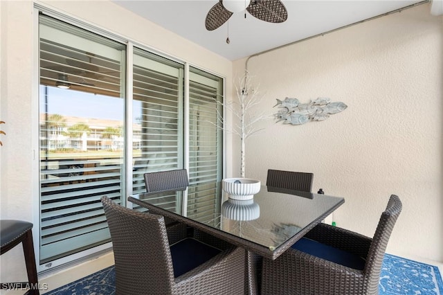 dining space with ceiling fan and a textured wall