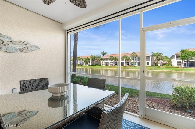 sunroom / solarium with ceiling fan, a water view, and a residential view