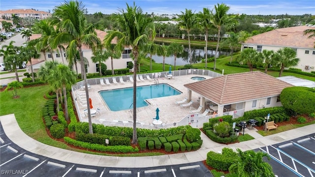 community pool with a yard, a water view, a patio, and a hot tub