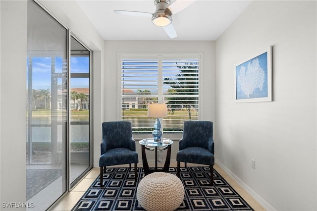 sitting room with tile patterned floors, a ceiling fan, and baseboards