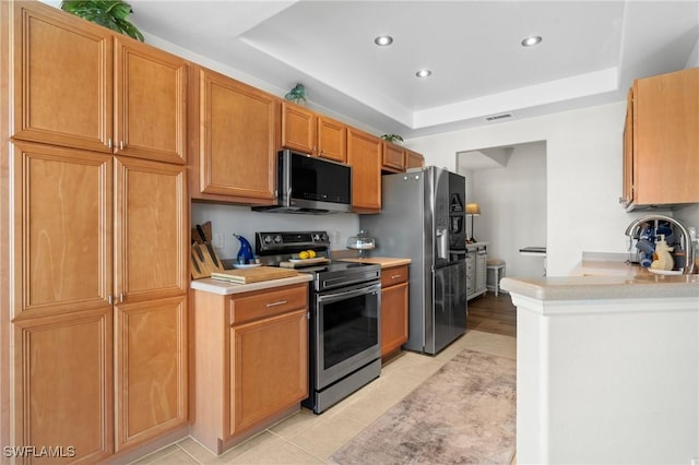 kitchen with visible vents, a raised ceiling, appliances with stainless steel finishes, light countertops, and recessed lighting