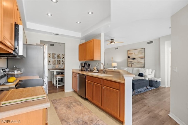 kitchen featuring visible vents, dishwasher, open floor plan, light countertops, and a sink