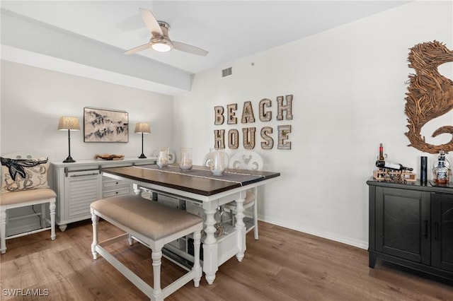 dining room with a dry bar, wood finished floors, a ceiling fan, and baseboards