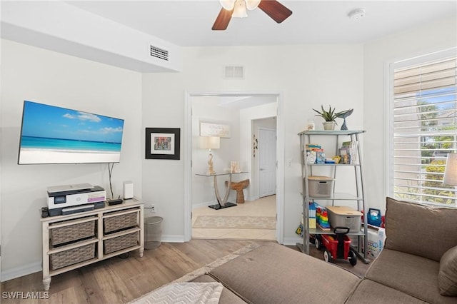 living area featuring light wood-style floors, visible vents, baseboards, and a ceiling fan