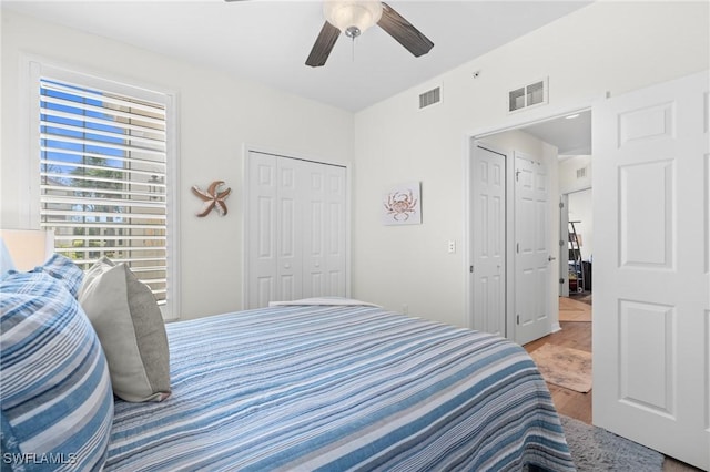 bedroom featuring ceiling fan, a closet, wood finished floors, and visible vents