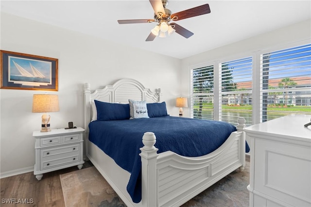 bedroom featuring dark wood-style floors, a ceiling fan, and baseboards