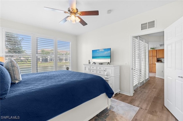 bedroom featuring baseboards, light wood-type flooring, visible vents, and a ceiling fan