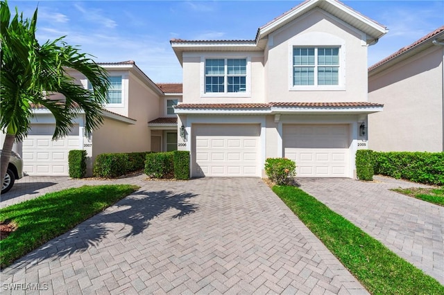 view of front of home with driveway, a tiled roof, an attached garage, and stucco siding