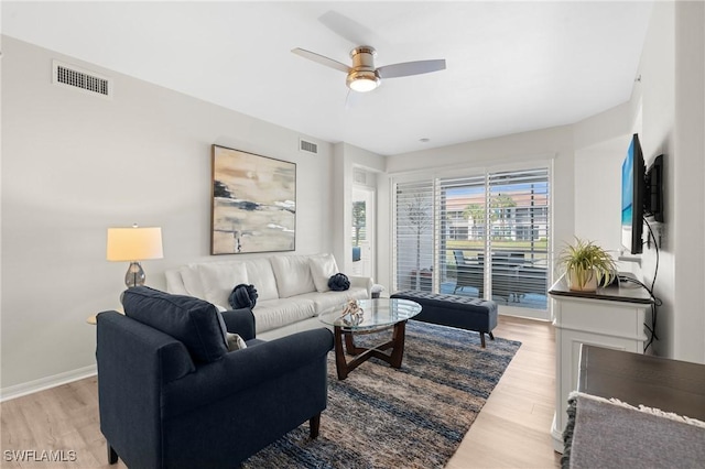 living area with baseboards, visible vents, and light wood finished floors