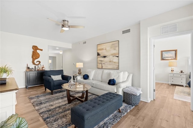 living area with light wood-style flooring, visible vents, and ceiling fan