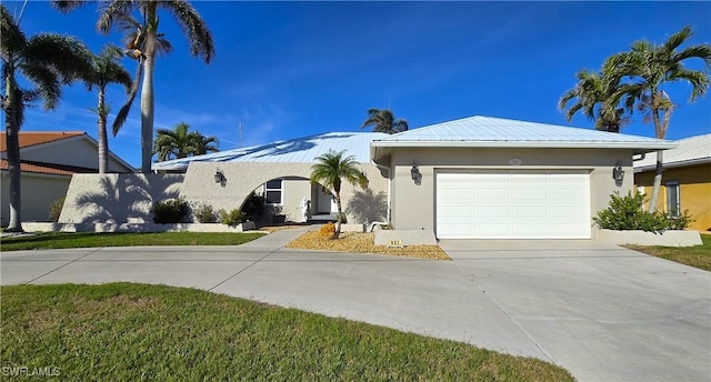 single story home with metal roof, concrete driveway, an attached garage, and stucco siding