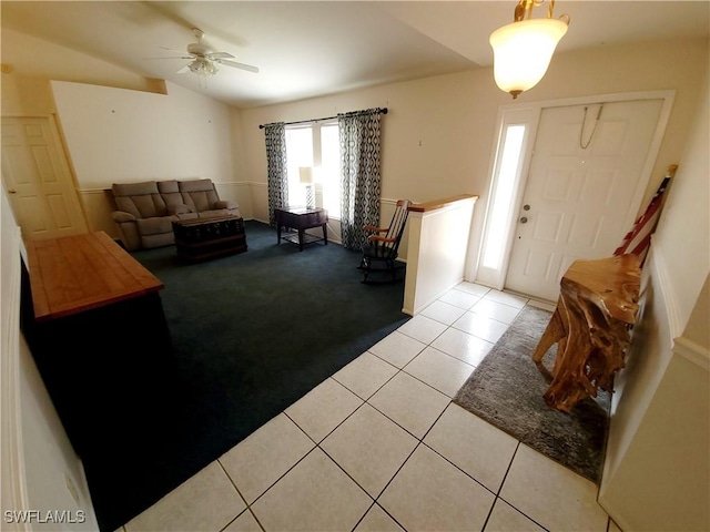 living area with light carpet, ceiling fan, vaulted ceiling, and light tile patterned flooring