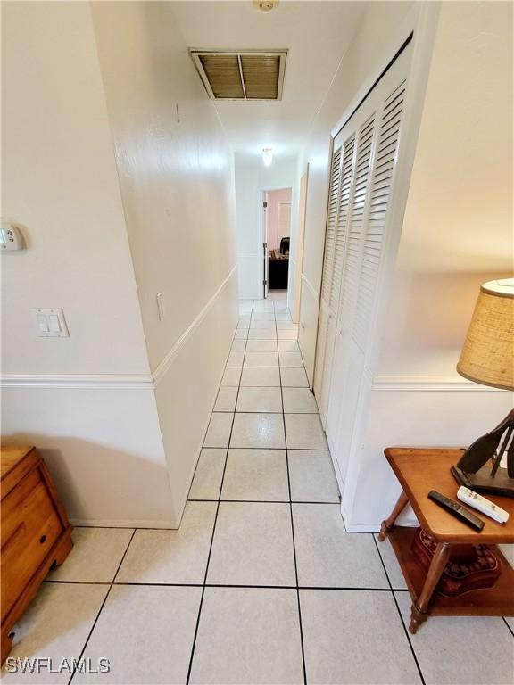 hallway featuring light tile patterned floors and visible vents