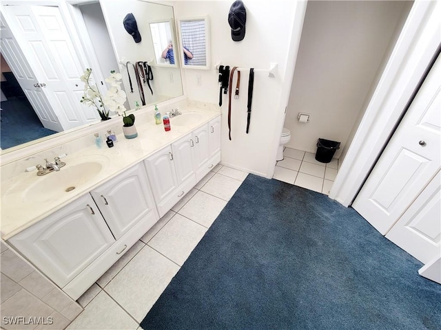 full bath with double vanity, a sink, toilet, and tile patterned floors