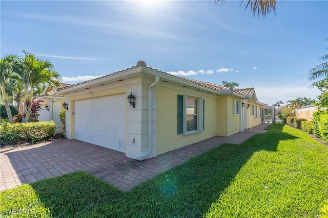 view of property exterior featuring a garage, a tile roof, a yard, and stucco siding