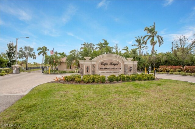 community / neighborhood sign featuring decorative driveway and a lawn