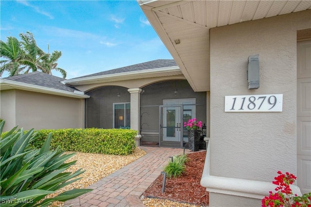 property entrance with a shingled roof and stucco siding