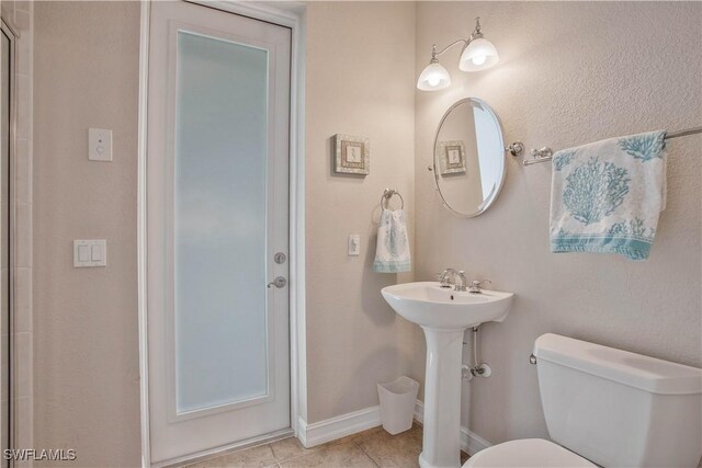 bathroom featuring toilet, tile patterned flooring, and baseboards