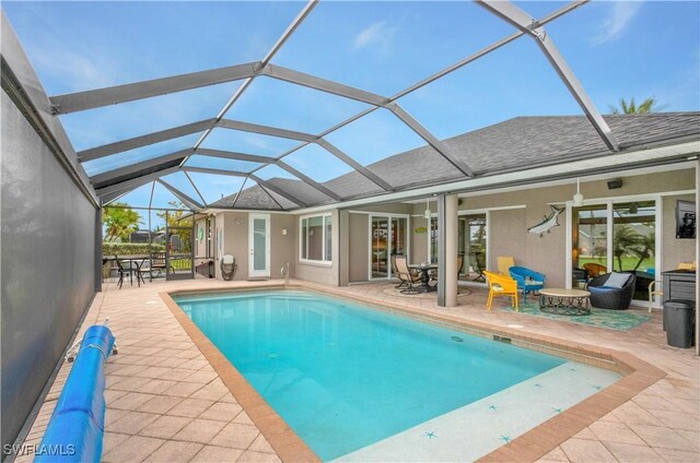 outdoor pool with a lanai, a ceiling fan, and a patio