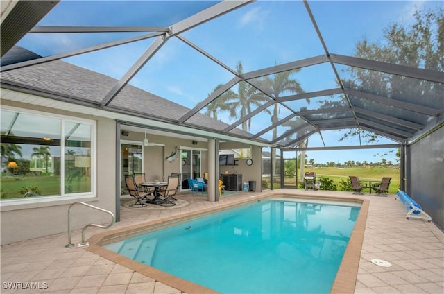 outdoor pool featuring ceiling fan, glass enclosure, and a patio