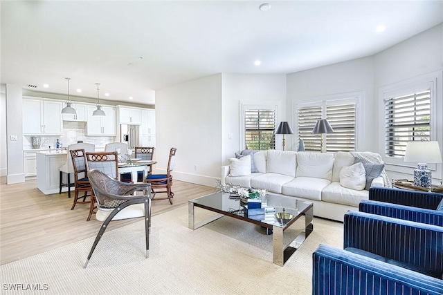 living room with baseboards, light wood finished floors, and recessed lighting