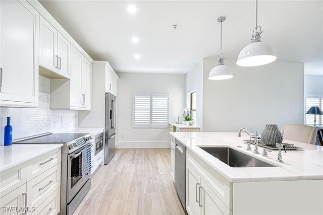 kitchen featuring white cabinets, a center island with sink, stainless steel appliances, and a sink