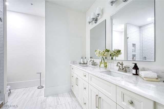 full bathroom with double vanity, baseboards, a tile shower, and a sink