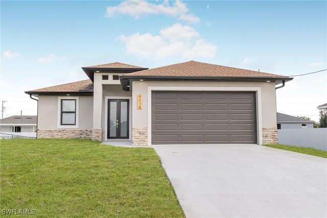 prairie-style home featuring a front lawn, stone siding, concrete driveway, and stucco siding