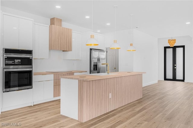 kitchen with white cabinets, a center island with sink, decorative light fixtures, and modern cabinets