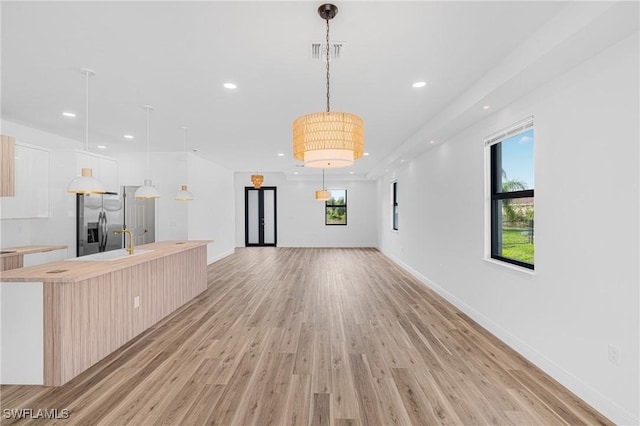 unfurnished living room with a healthy amount of sunlight, light wood finished floors, visible vents, and recessed lighting