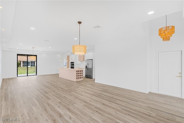 unfurnished living room featuring light wood finished floors, baseboards, visible vents, and recessed lighting
