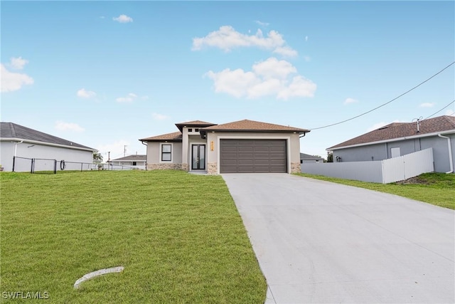prairie-style house with a garage, concrete driveway, fence, a front lawn, and stucco siding