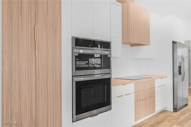 kitchen with light countertops, light wood-style flooring, appliances with stainless steel finishes, white cabinetry, and modern cabinets