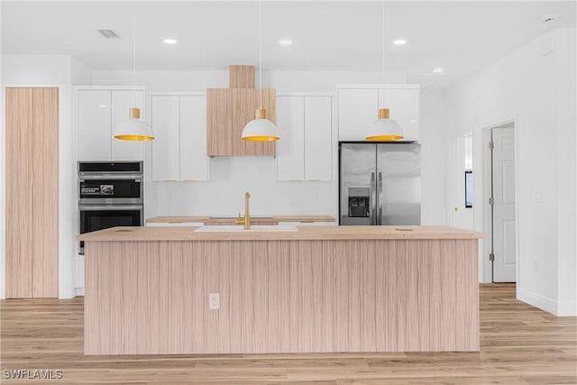 kitchen with a center island with sink, appliances with stainless steel finishes, white cabinetry, a sink, and modern cabinets