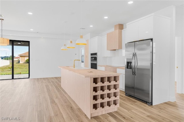 kitchen with stainless steel appliances, white cabinets, a kitchen island with sink, and hanging light fixtures