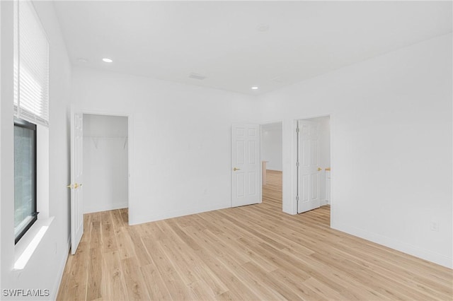 empty room with light wood finished floors, a wealth of natural light, and baseboards
