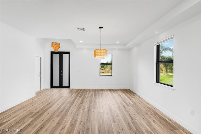 empty room with a healthy amount of sunlight, visible vents, light wood-style flooring, and baseboards