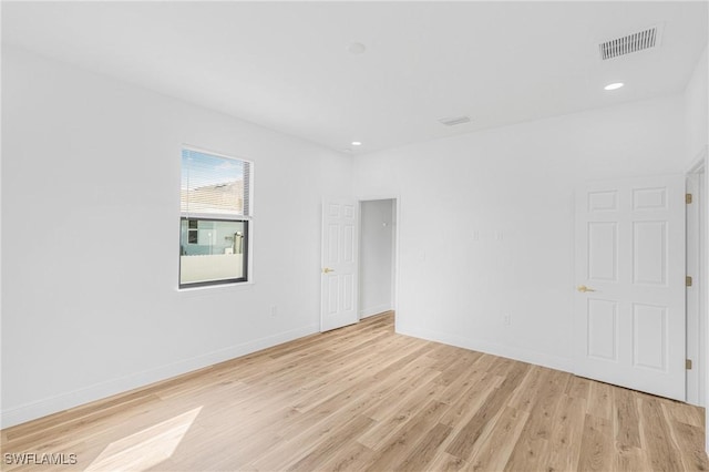 spare room with light wood finished floors, recessed lighting, visible vents, and baseboards