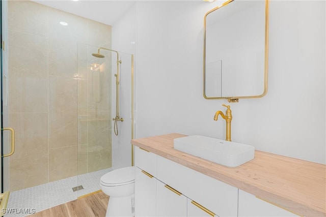 bathroom with vanity, a stall shower, wood finished floors, and toilet