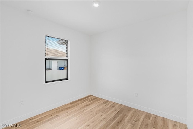 spare room featuring light wood finished floors and baseboards