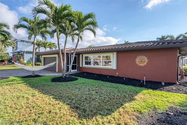 view of front facade with a garage, driveway, a front lawn, and stucco siding