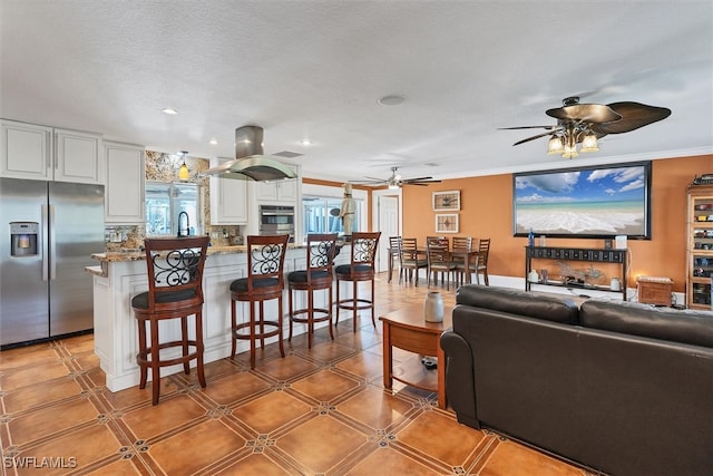 living room with a textured ceiling, ornamental molding, a ceiling fan, and recessed lighting