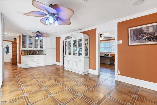 interior space featuring baseboards, visible vents, ornamental molding, and ceiling fan