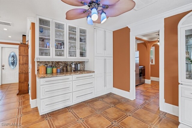 bar with ornamental molding, arched walkways, visible vents, and backsplash