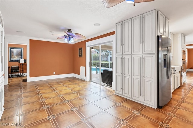 unfurnished living room with a textured ceiling, ornamental molding, a ceiling fan, and baseboards