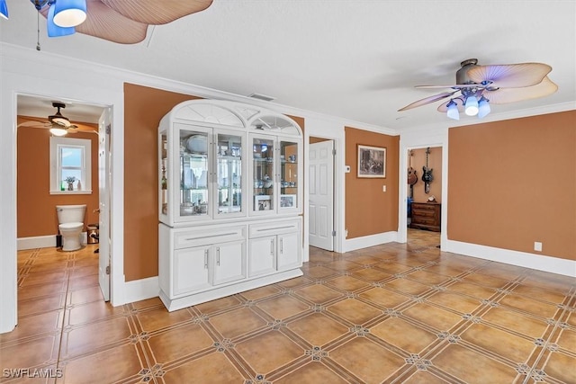 interior space with ornamental molding, visible vents, ceiling fan, and baseboards